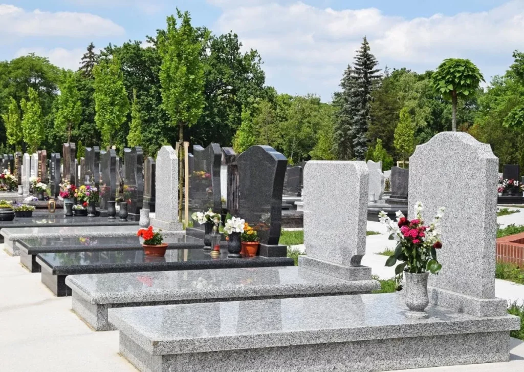 Pierres tombales en granit alignées dans un cimetière paysager