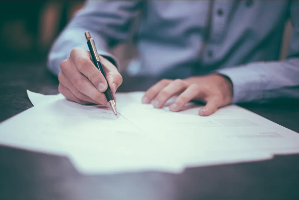 Les mains d'une personne remplissant des documents administratifs pour l'accompagnement des familles
